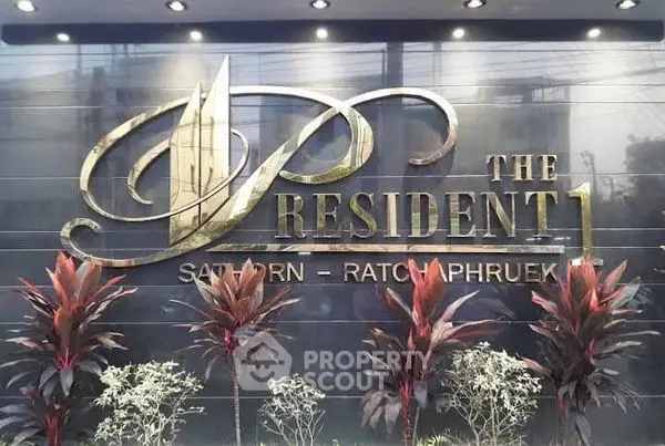 Elegant entrance sign of The President 1 Sathorn-Ratchaphruek with lush plants.