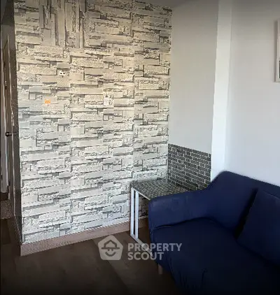 Cozy living room with modern stone accent wall and comfortable blue sofa.
