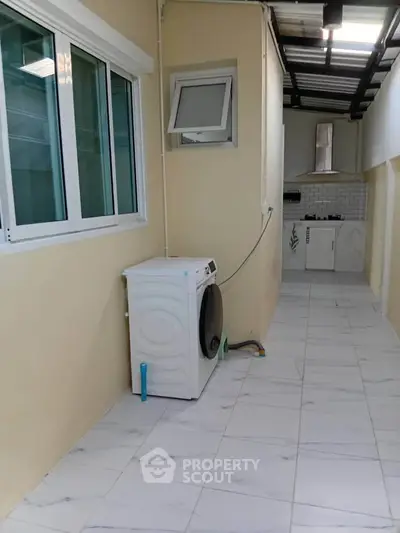 Modern laundry area with washing machine and sleek kitchen setup in a bright, tiled space.