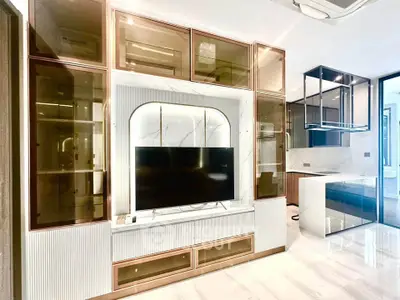 Luxurious modern living room with sleek built-in entertainment center and elegant glass cabinetry.