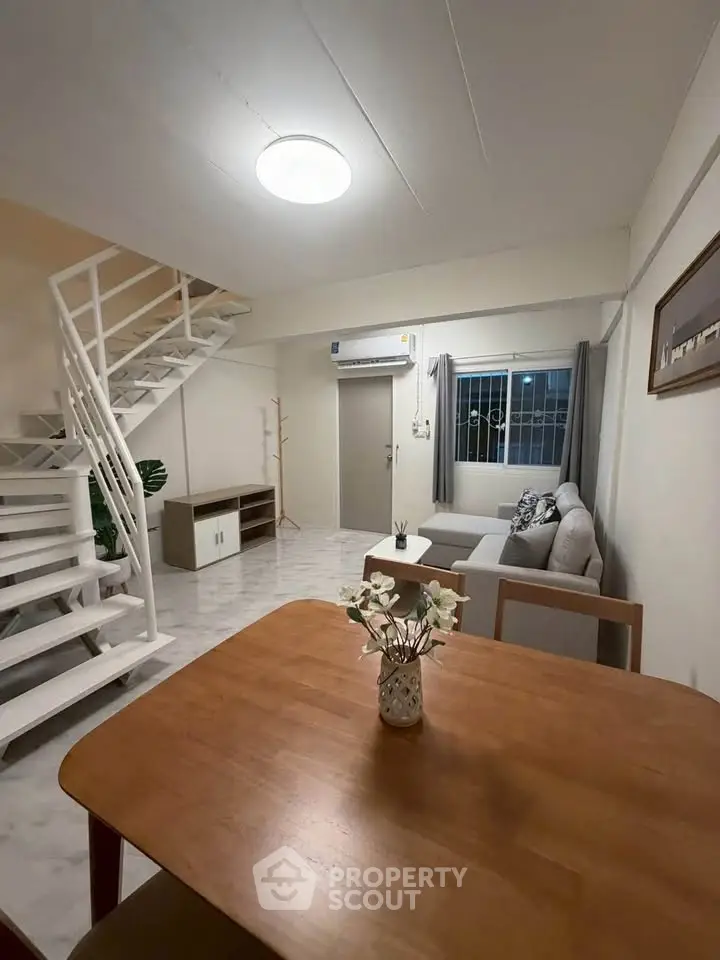 Spacious living room with modern staircase and cozy seating area in a stylish apartment.