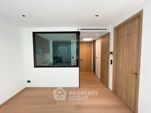 Modern apartment interior with wooden floors and glass partition, showcasing sleek design and open layout.