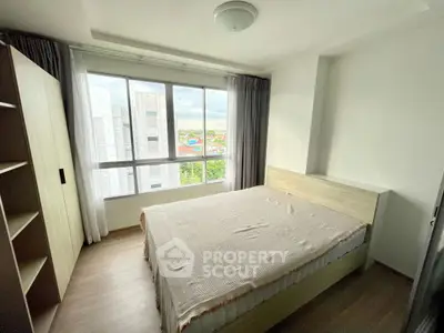 Bright bedroom with large window and modern furnishings in urban apartment.