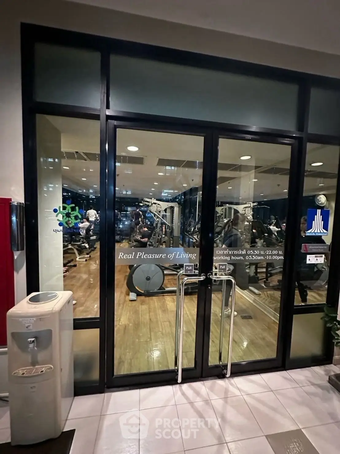 Modern gym entrance with glass doors and fitness equipment visible inside.
