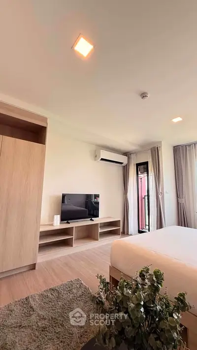 Spacious modern bedroom with TV, air conditioning, and balcony access, perfect for comfort and relaxation.