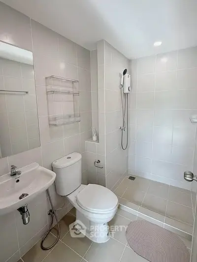 Modern bathroom with sleek tiles and contemporary fixtures, featuring a shower and elegant sink design.