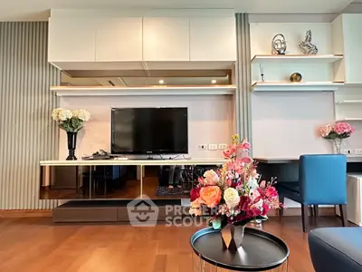 Modern living room with elegant decor and flat-screen TV, featuring stylish shelving and vibrant floral arrangements.
