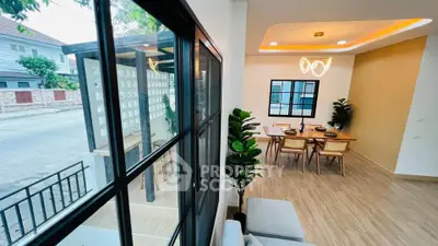 Modern open-plan living and dining area with stylish lighting and large windows in a contemporary home.
