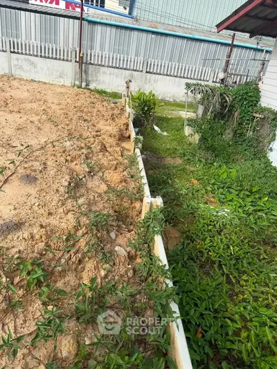 Vacant land plot with partial fencing and greenery, ideal for development.