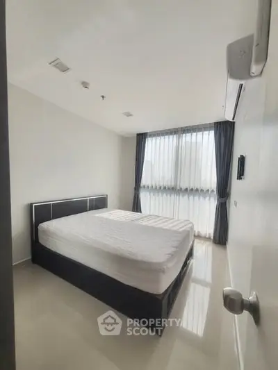 Bright and airy bedroom with large window and modern furnishings, perfect for relaxation.