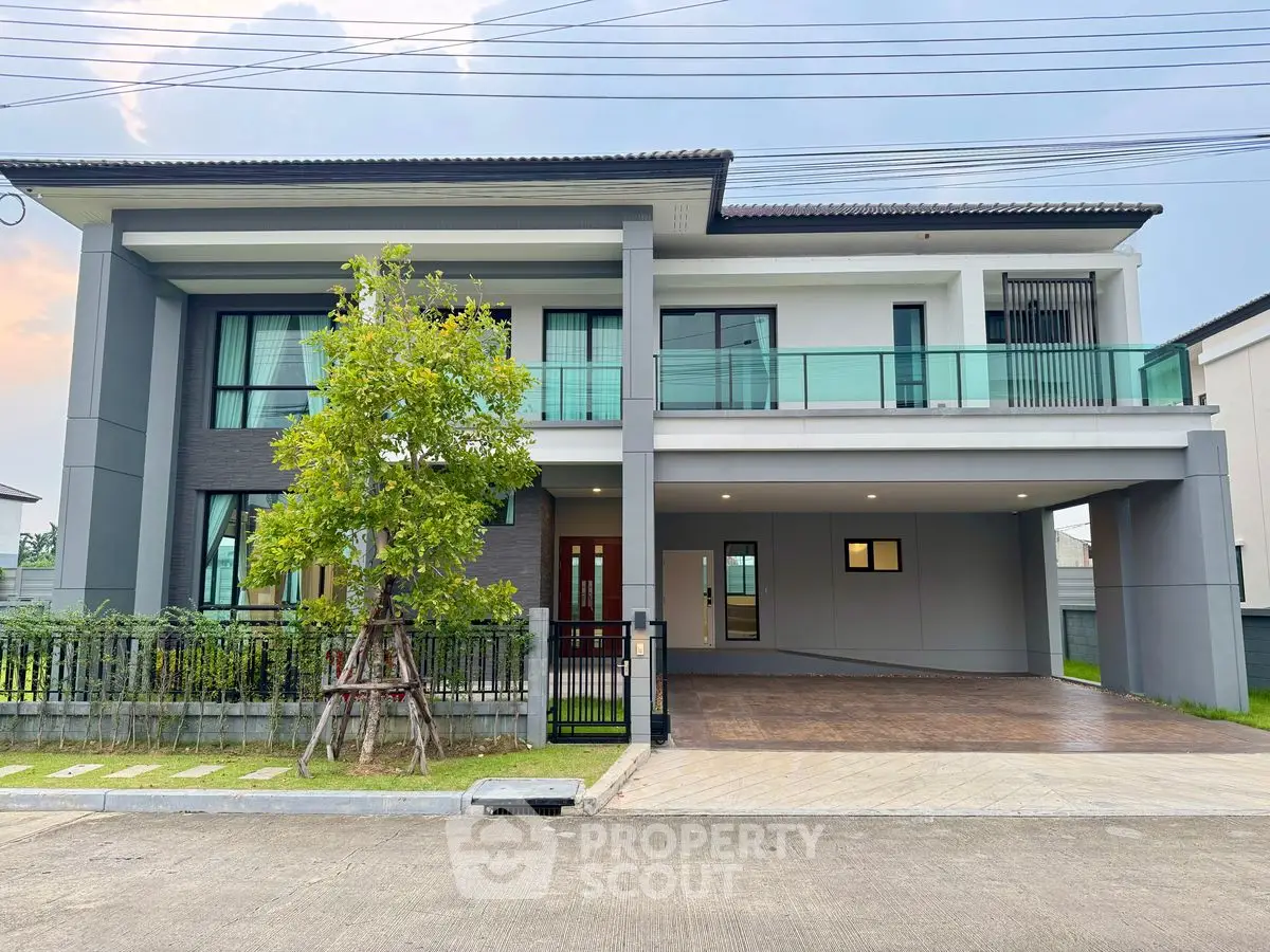 Modern two-story house with spacious driveway and glass balcony in a serene neighborhood.