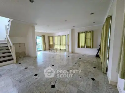 Spacious living room with marble flooring and large windows in a modern home.