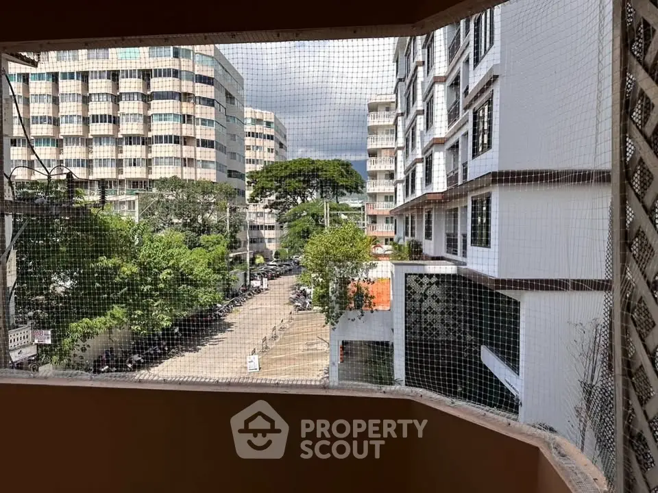 Urban view from a balcony showcasing modern apartment buildings and lush greenery.