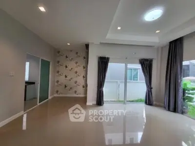 Spacious modern living room with large windows and elegant curtains, perfect for natural light.
