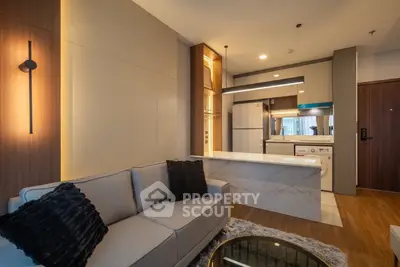 Modern living room with open kitchen, stylish lighting, and cozy sofa in a contemporary apartment.