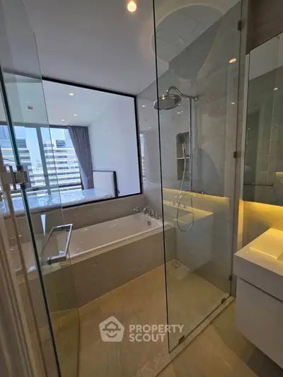 Luxurious bathroom with glass shower and bathtub offering city view