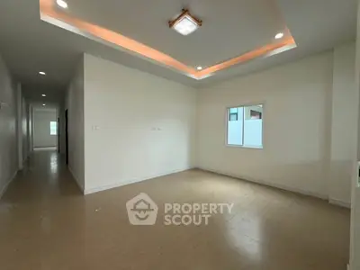Spacious empty room with modern ceiling lights and natural light from window, ideal for customization.