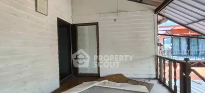 Spacious balcony with wooden flooring and partial roof cover, ideal for relaxation.