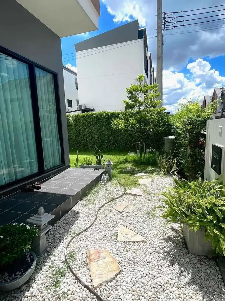 Charming garden with stone pathway and lush greenery in modern residential area.