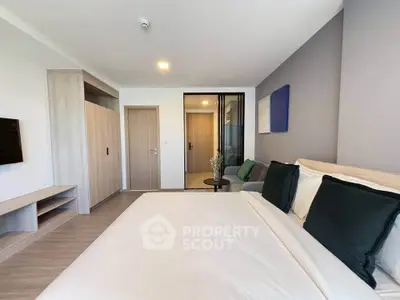 Modern bedroom with stylish decor and ample natural light, featuring a cozy bed and sleek furnishings.
