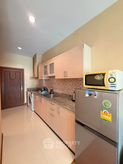 Modern kitchen with sleek cabinets, granite countertops, and stainless steel appliances in a cozy apartment.