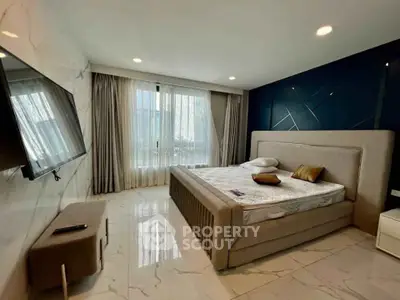 Luxurious bedroom with modern decor, large windows, and a wall-mounted TV in a high-end apartment.