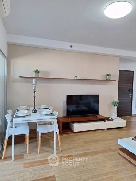 Modern living room with dining area and TV, featuring stylish decor and wooden flooring.