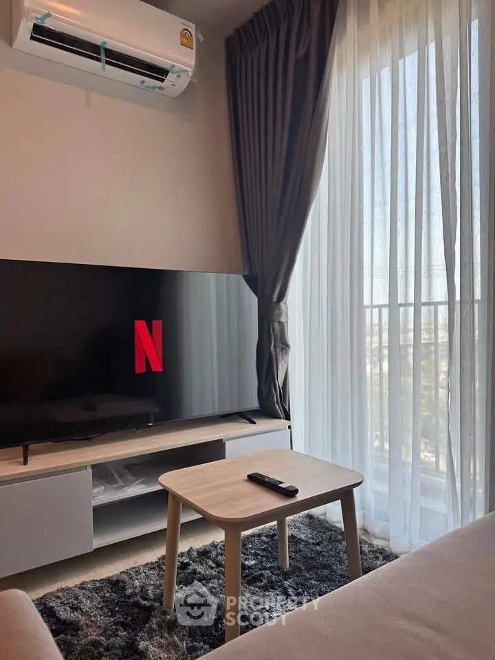 Cozy living room with modern TV setup and large window view.