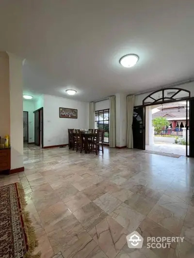 Spacious living room with polished tile flooring, ample natural light, and direct access to outdoor areas, ideal for family gatherings and entertaining guests.