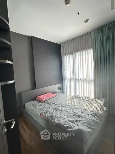 Cozy bedroom with natural light and modern decor, featuring a comfortable bed and stylish curtains.