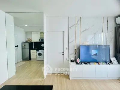 Modern living room with sleek TV setup and open kitchen view.