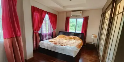 Cozy bedroom with wooden flooring and large windows offering natural light