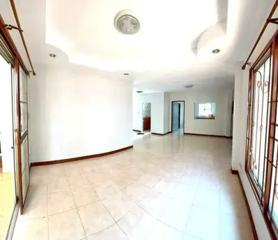 Spacious open-plan living area with large windows and tiled flooring