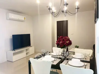 Modern dining area with elegant chandelier and sleek TV setup