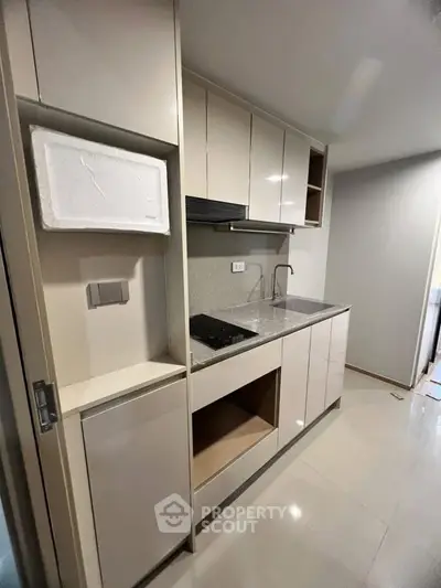 Modern compact kitchen with sleek cabinetry and built-in appliances in a stylish apartment.