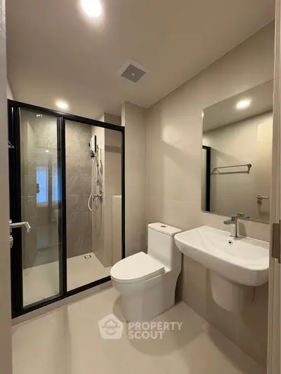 Modern bathroom with sleek fixtures and glass shower enclosure in a contemporary apartment.