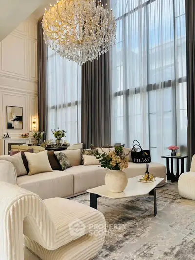 Luxurious living room with high ceilings, elegant chandelier, and plush seating.