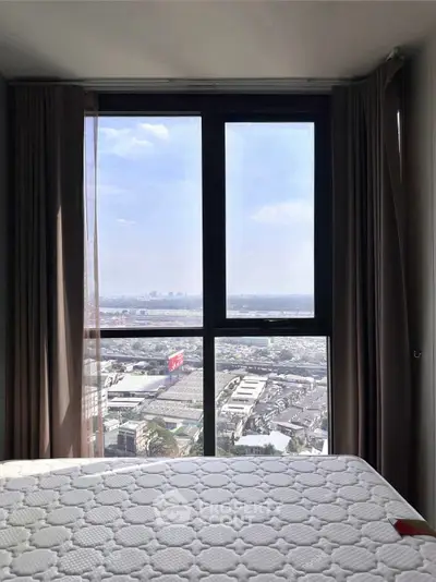 Spacious bedroom with stunning city view through large window, perfect for urban living.