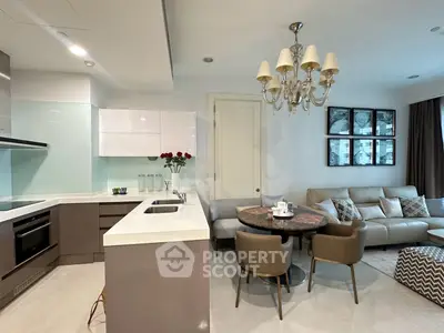Modern open-layout kitchen and living room with elegant chandelier and cozy seating area.
