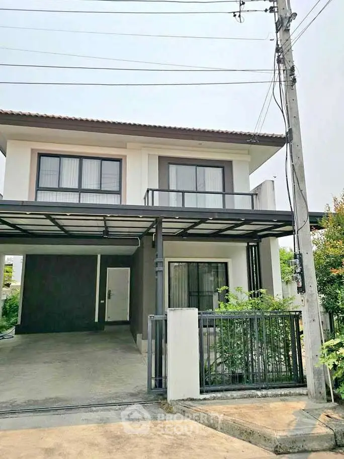 Modern two-story house with driveway and balcony in a suburban neighborhood.