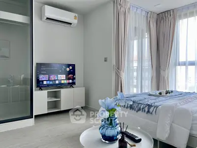 Modern bedroom with sleek decor and natural light, featuring a smart TV and air conditioning.