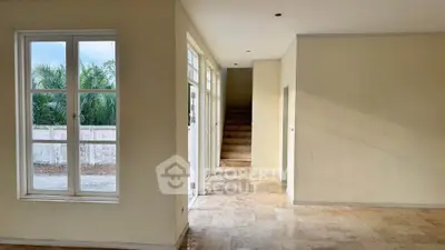 Spacious interior with large windows and staircase, offering natural light and garden view.