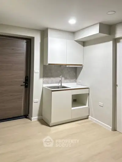 Modern compact kitchen with sleek cabinetry and wood flooring in a contemporary apartment