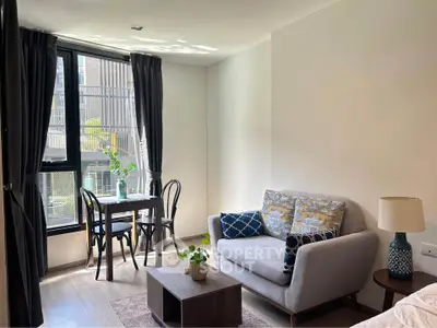 Chic modern living room with cozy sofa and dining area, flooded with natural light from large windows.