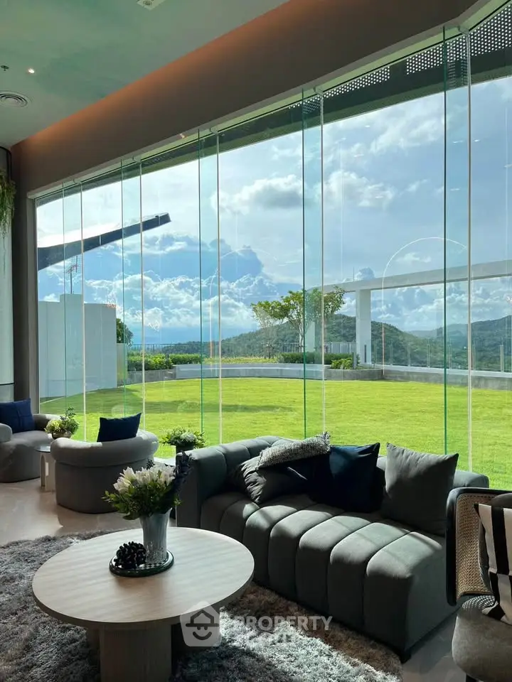 Luxurious living room with panoramic glass walls offering stunning mountain views and lush green lawn.