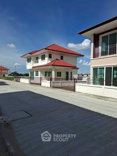 Charming two-story house with red roof and spacious driveway in a serene neighborhood.