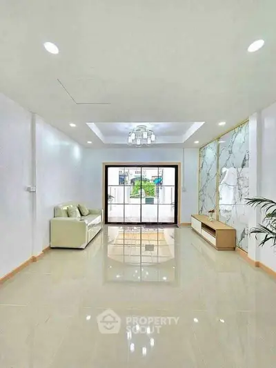Spacious modern living room with elegant marble accent wall and large window view.