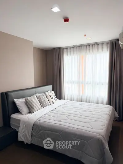 Modern bedroom with cozy bedding and natural light from large window