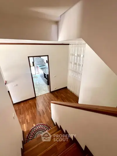 Elegant staircase with wooden flooring leading to a bright, open living space.