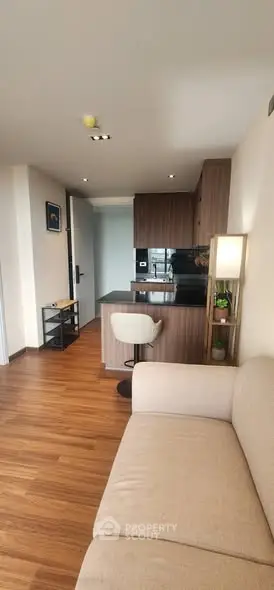 Modern living room with open kitchen layout and stylish wooden flooring.